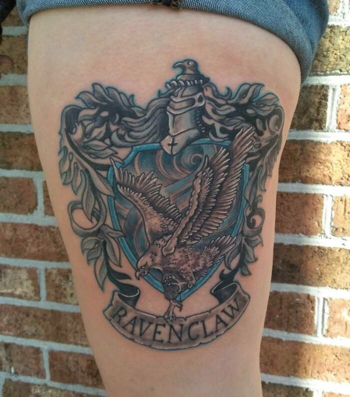 Ravenclaw crest tattoo on a thigh, featuring an eagle and intricate detailing, perfect for any Harry Potter fan.