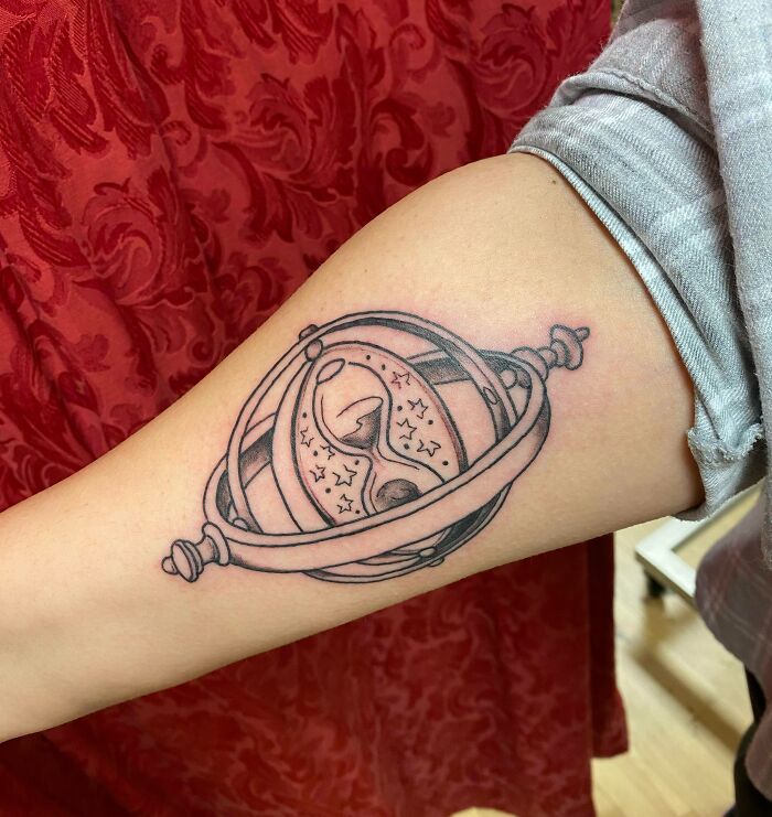 Arm tattoo of a time turner with stars, inspired by the wizarding world of Harry Potter.