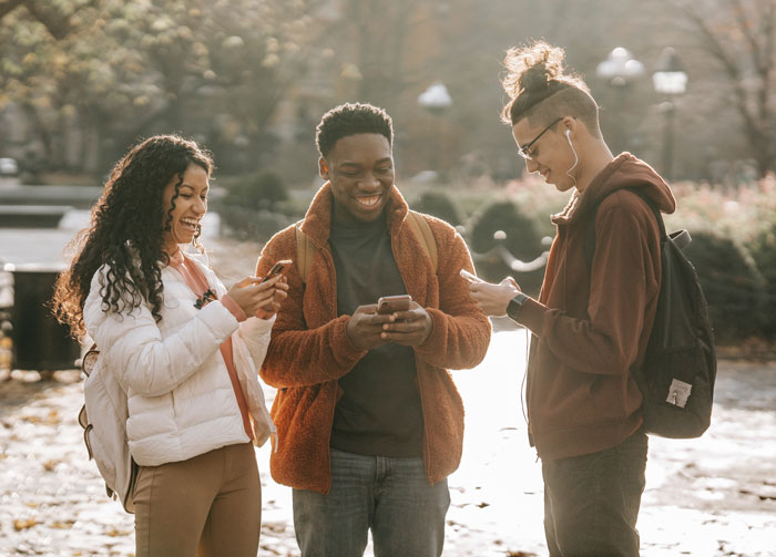 Friends watching phones and laughing