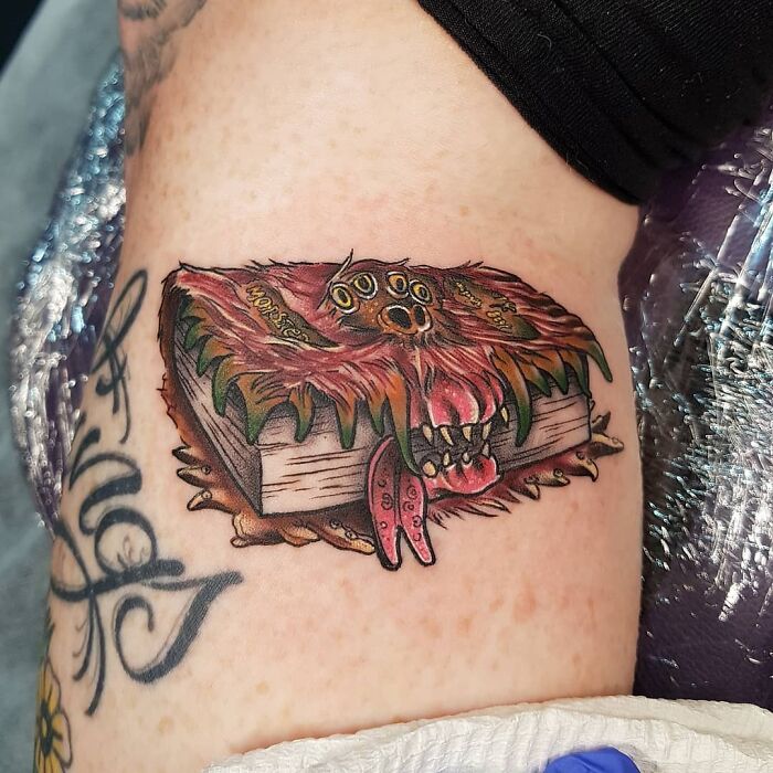 Harry Potter tattoo of the Monster Book of Monsters on an arm, showcasing vivid details and colors.