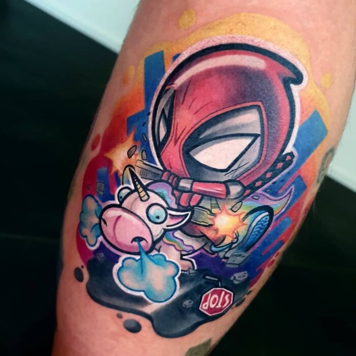 Colorful Marvel tattoo featuring Deadpool and a unicorn in a vibrant, comic-style design, showcasing superhero art.