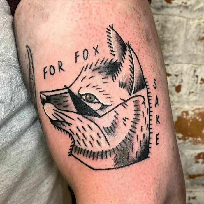 Tattoo of a fox's face with text, inked on an arm.