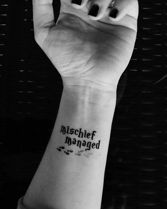 Close-up of a wrist tattoo with the phrase "Mischief Managed," inspired by Harry Potter.