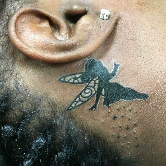 Fairy tattoo near ear, featuring detailed wings and stars for a unique ear tattoo design.