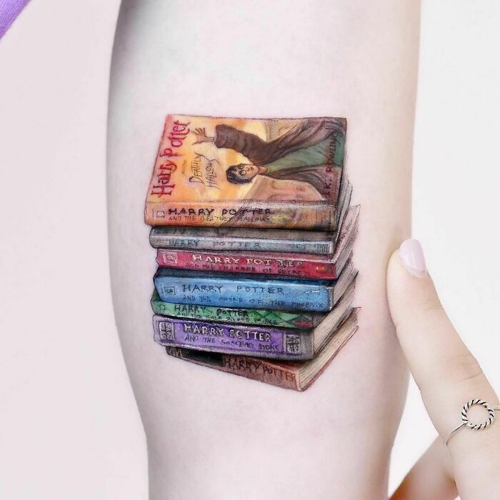 Harry Potter tattoo of a stack of books on a person's arm, showcasing detailed and colorful designs from the series.