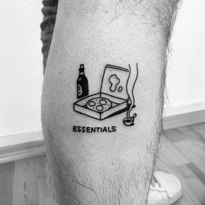 Tattoo of pizza, drink, and smoke labeled "Essentials" on a leg, featuring word tattoo design.