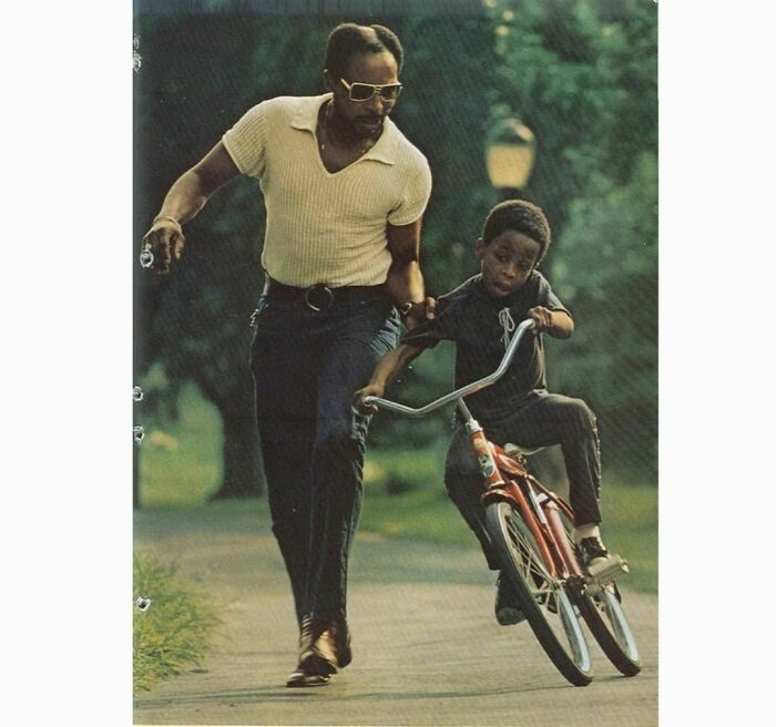 Man teaching his son how too ride a bike in the park 