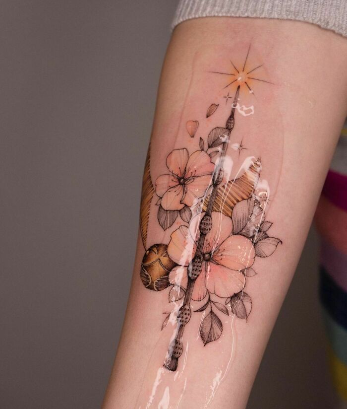 Harry Potter-themed tattoo with flowers and wand design on forearm, ideal for ultimate fans of the Wizarding World.