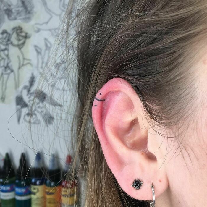 ear tattoo of a minimalistic line and dot design