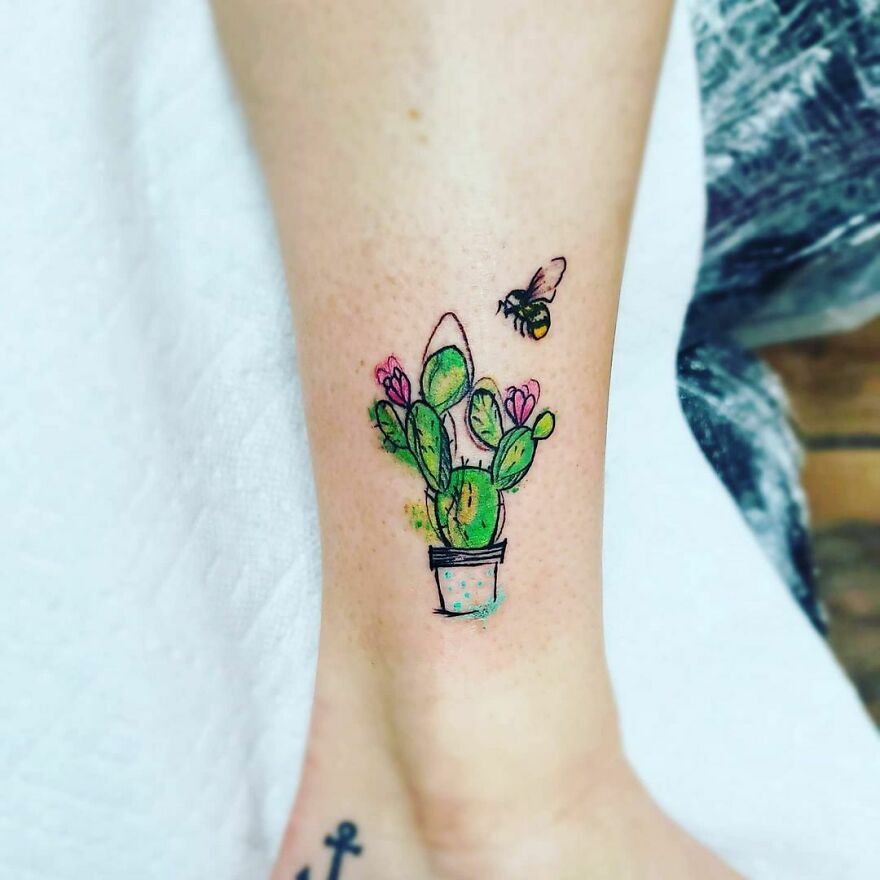 cactus in a pot with a bee nearby colorful tattoo on the leg