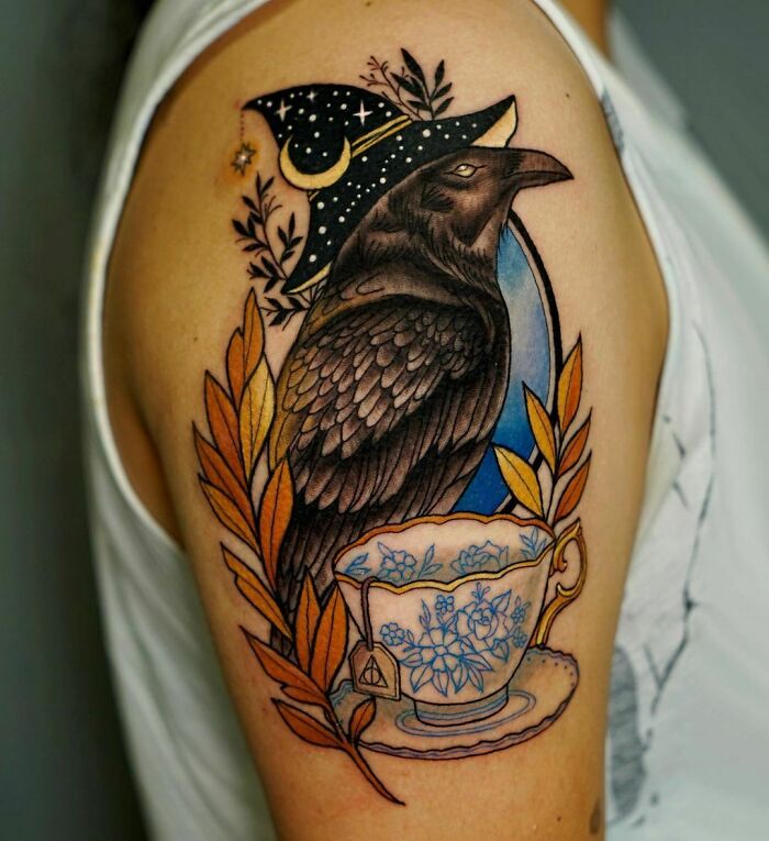 Harry Potter tattoo featuring a raven in a wizard hat with tea cup and leaves on an arm.