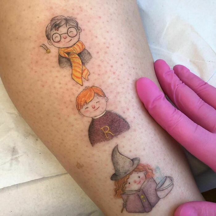 Harry Potter tattoos depicting iconic characters in a cute style on someone's leg, with a gloved hand touching them.