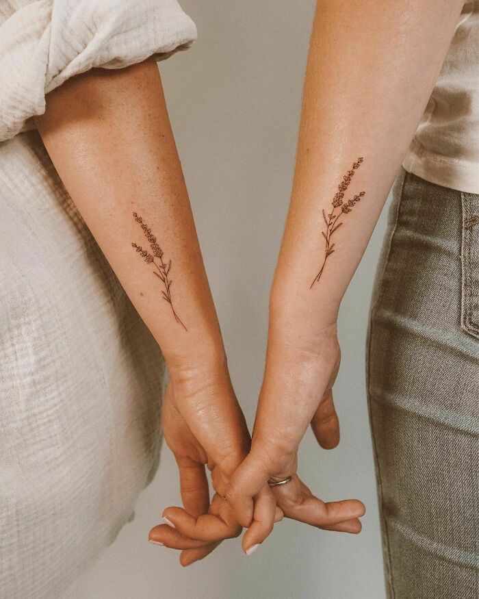 Matching floral friend tattoos on forearms, symbolizing eternal friendship.