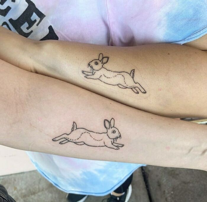 Matching rabbit tattoos on forearms symbolize best friend connection and friendship.