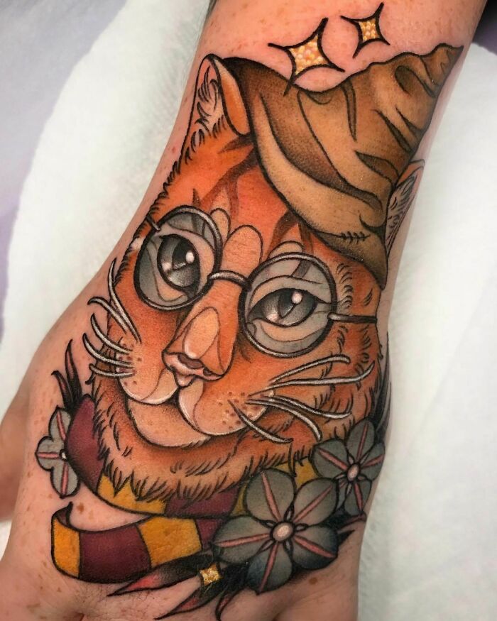 Cat in glasses tattoo with sorting hat and scarf, inspired by Harry Potter.