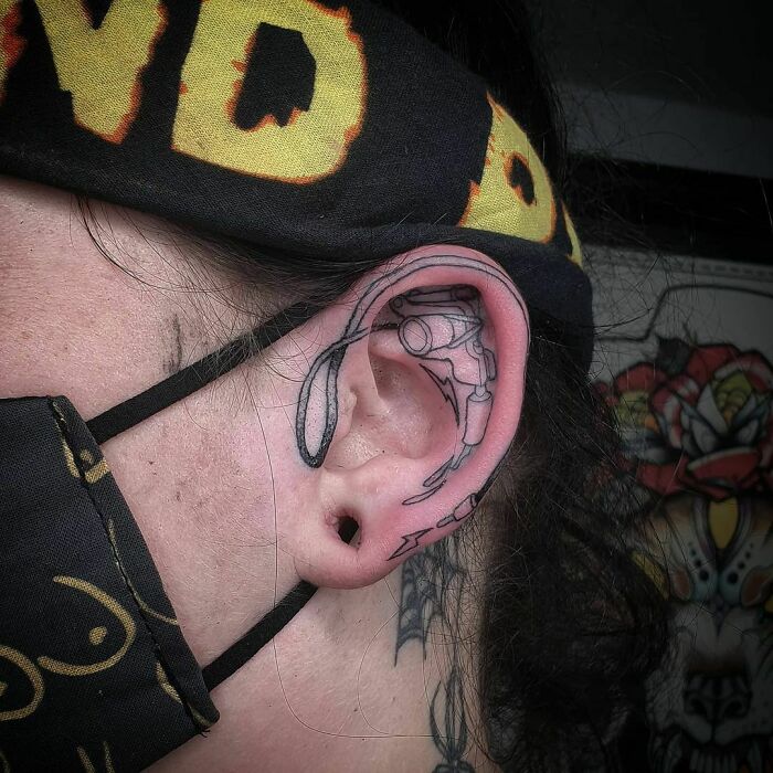 Ear tattoo featuring intricate black linework and abstract design.