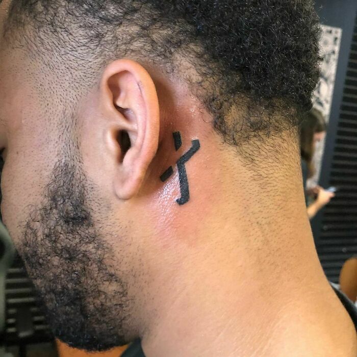 ear tattoo of a negative space cross