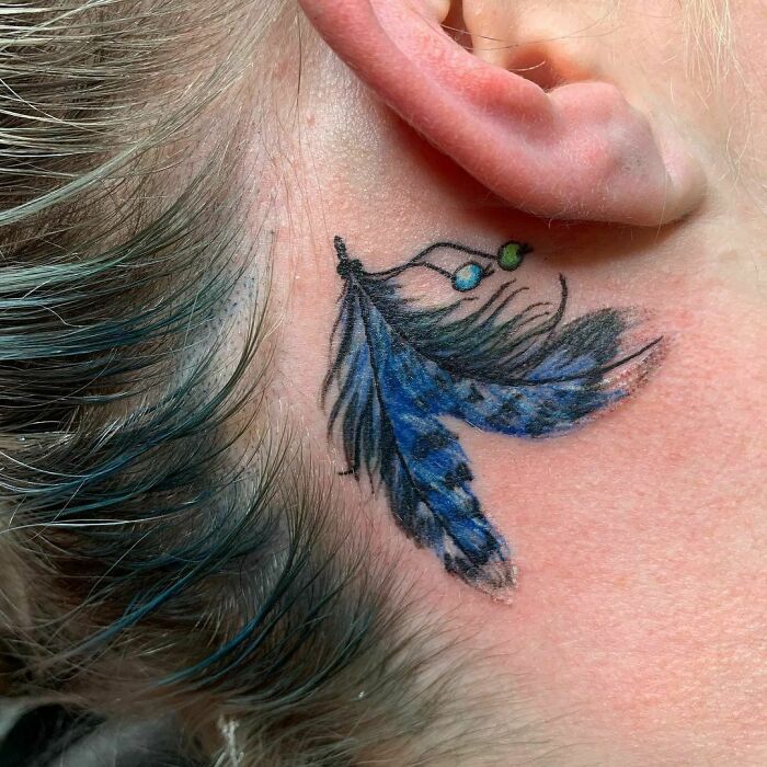 ear tattoo of a pair of blue feathers