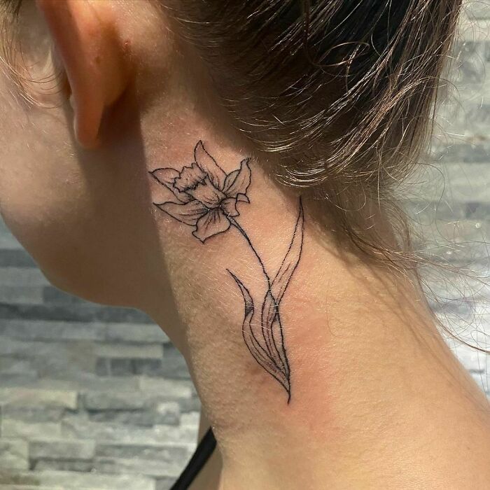 ear and neck tattoo of a daffodil flower