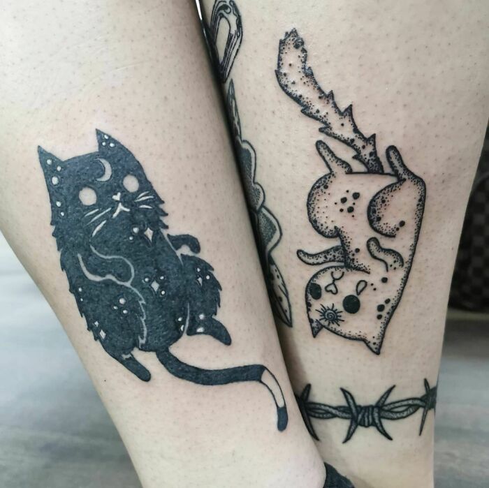 Matching best friend tattoos of cats with celestial designs on legs.