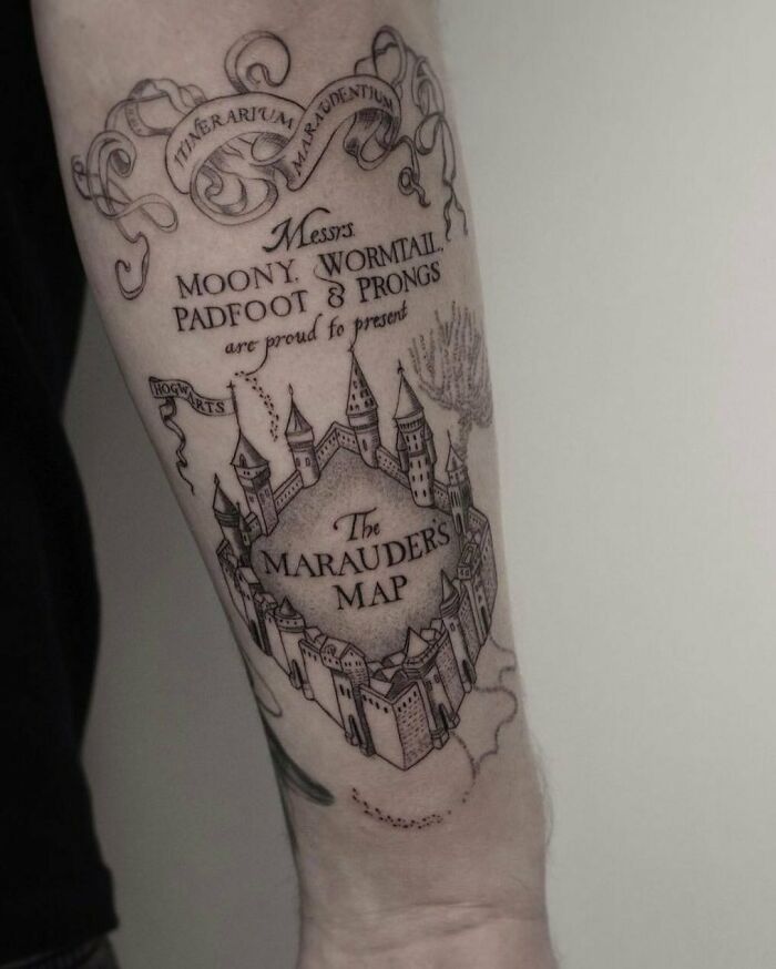 Tattoo of The Marauder's Map from Harry Potter on an arm, featuring intricate castle and scroll designs.