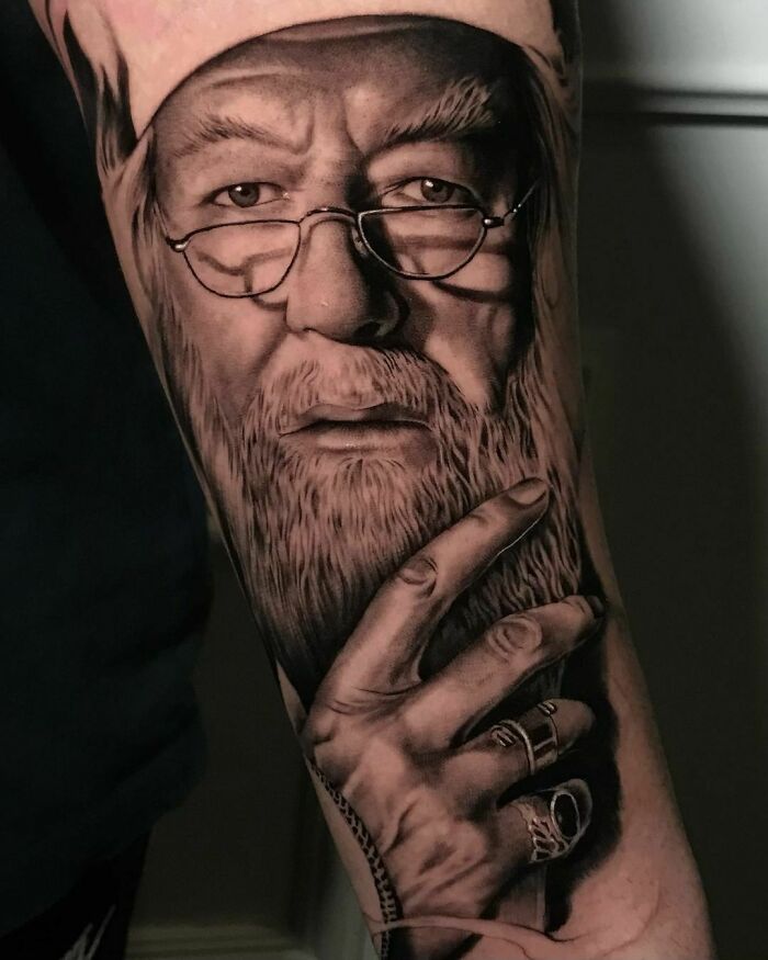 Realistic Harry Potter tattoo depicting an elderly man with glasses and a long beard, covering the forearm.