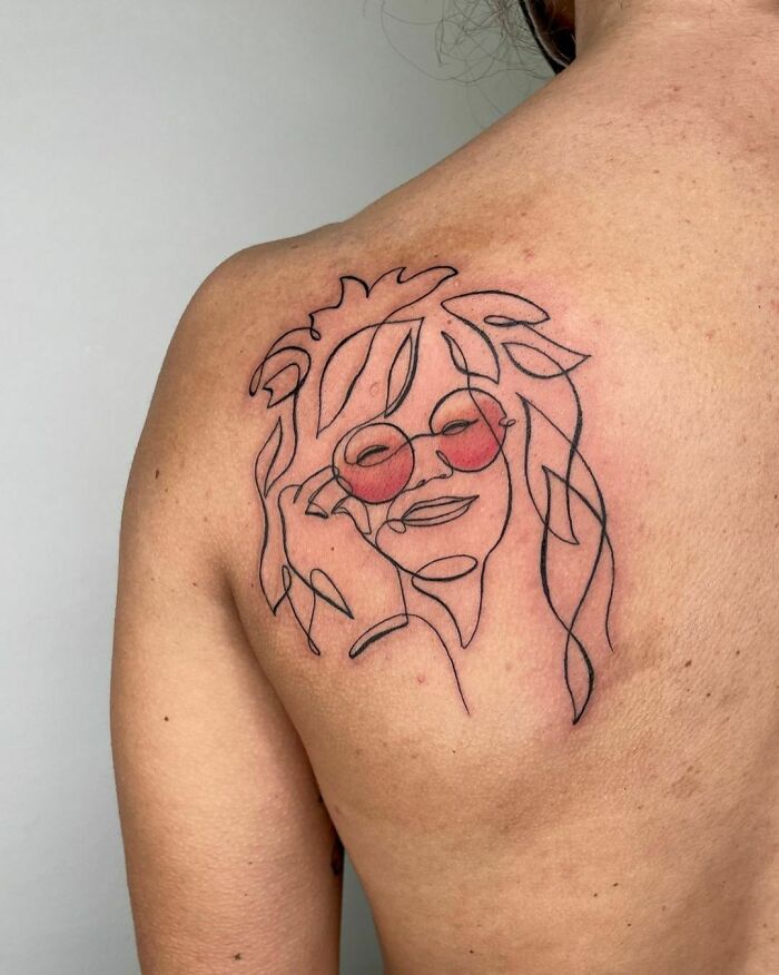 Woman with sunglasses single line shoulder tattoo