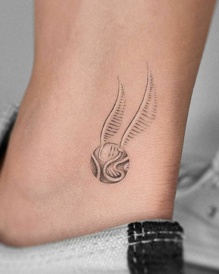 Golden Snitch tattoo on ankle, showcasing intricate Harry Potter design.
