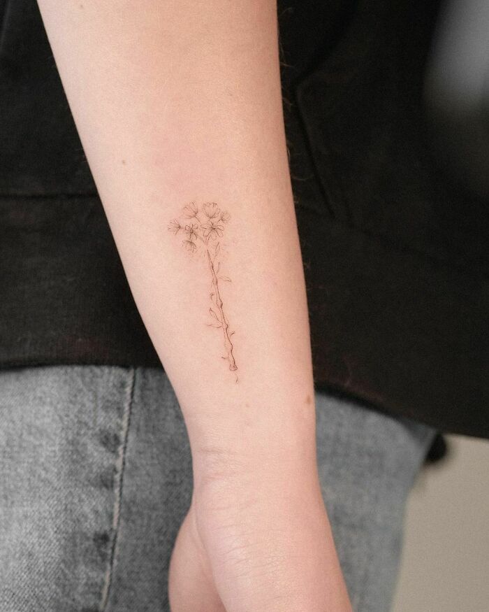 Delicate Harry Potter-themed floral tattoo on a person's forearm, showcasing subtle artistry and a magical touch.