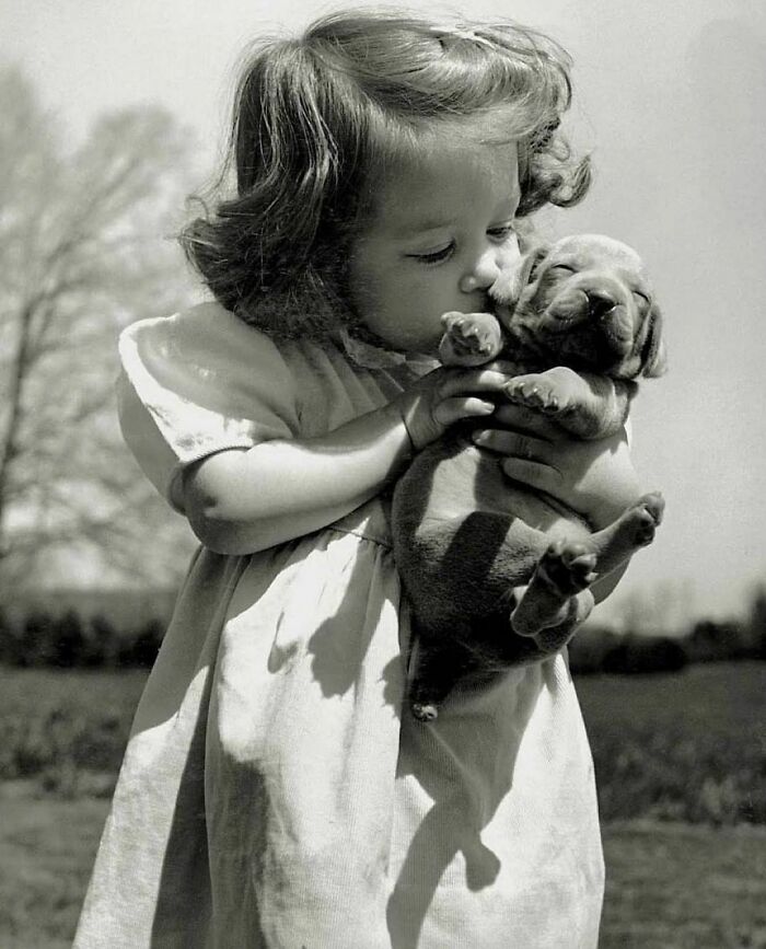 Una niña de 3 años besa a un cachorro, 1950