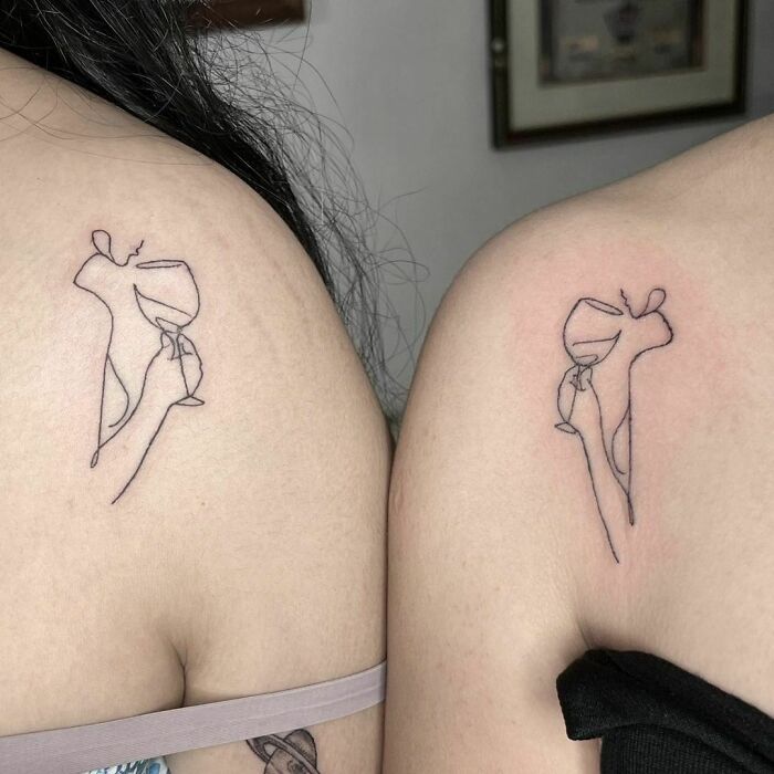 Minimalist best friend tattoos of wine glasses on shoulders symbolizing friendship.