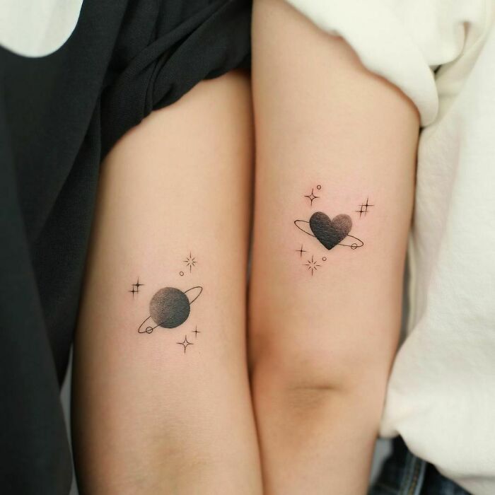 Matching planet and heart tattoos symbolizing friendship.