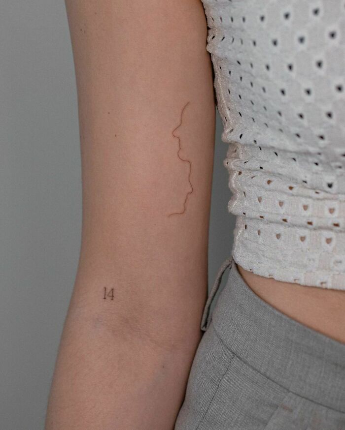 Single line 2 faces arm tattoo
