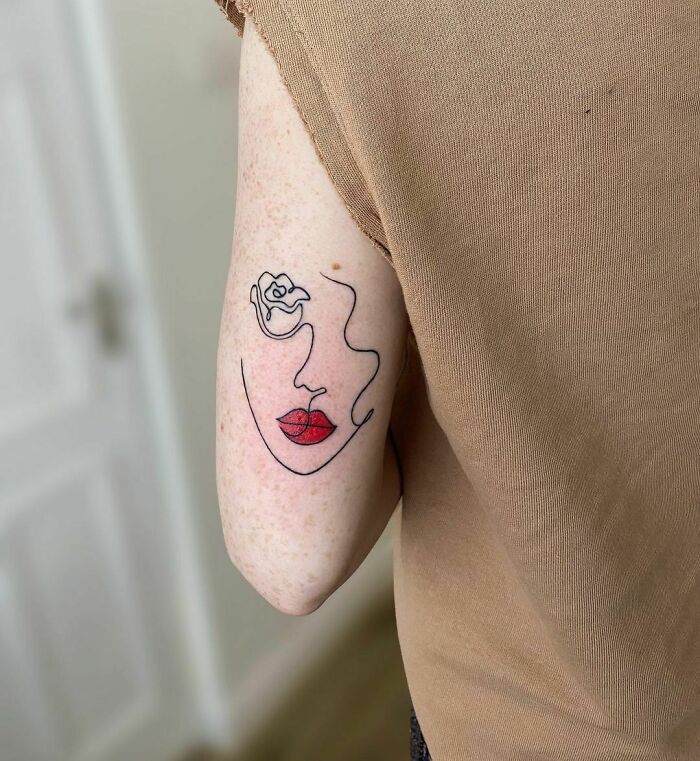 Line face with red lips back arm tattoo