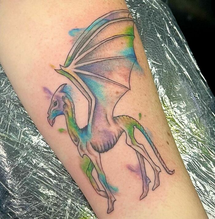 Colorful Thestral tattoo inspired by Harry Potter on forearm.