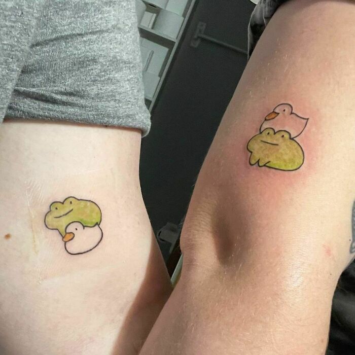 Two arms showcasing matching best friend tattoos of a frog and duck duo.