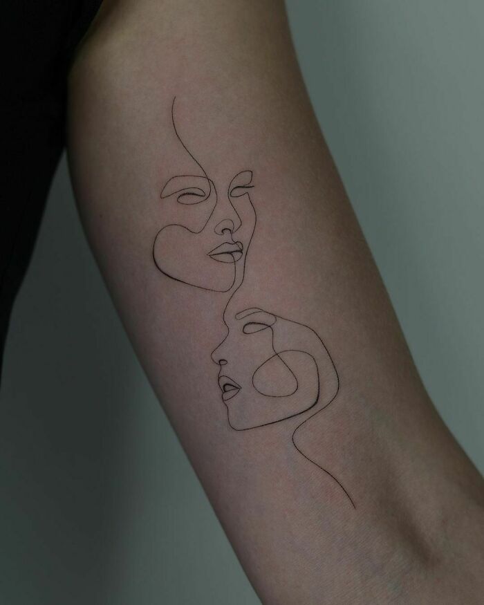 Single line faces arm tattoo
