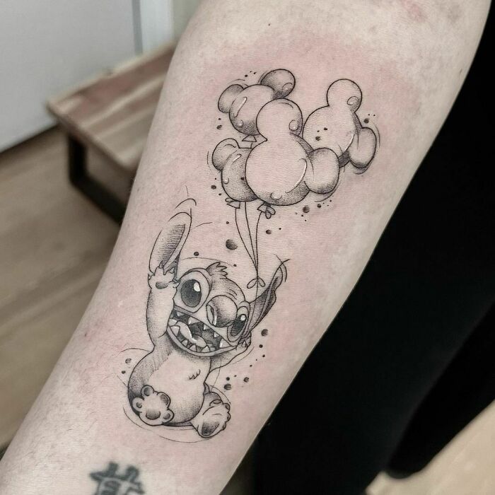 Stitch holding balloons arm tattoo
