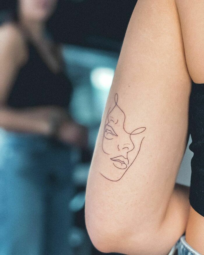 Single line faces arm tattoo