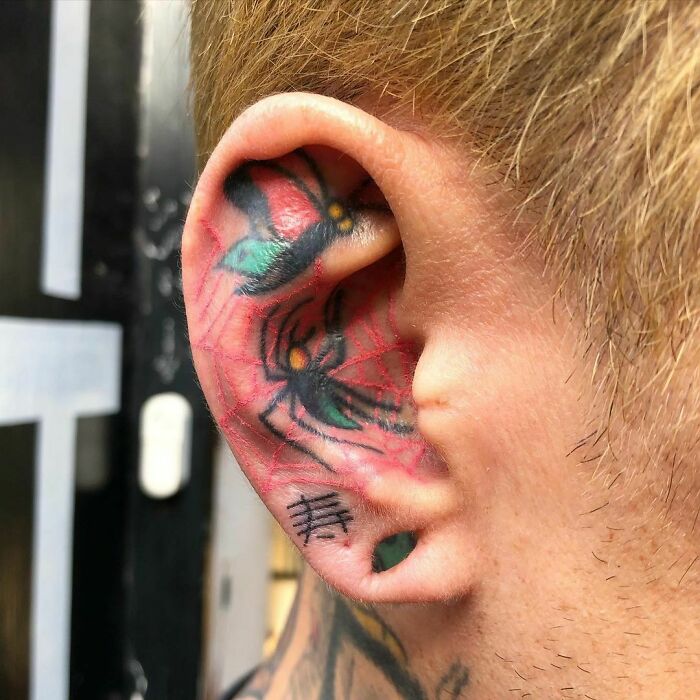 Colorful spider web ear tattoo with flower details.