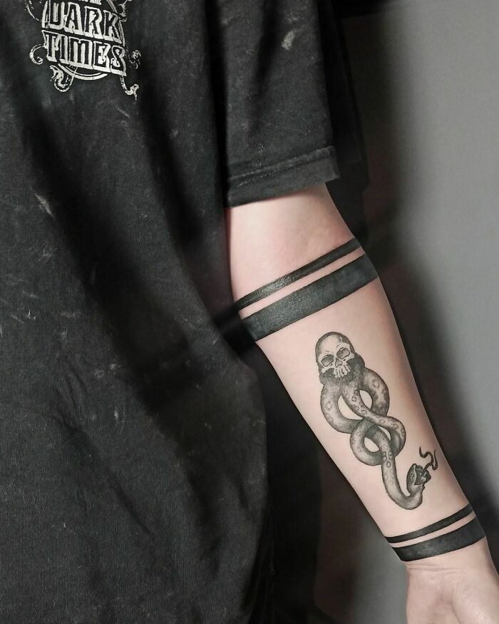 Tattoo of the Dark Mark from Harry Potter on forearm, with bold black bands above and below.