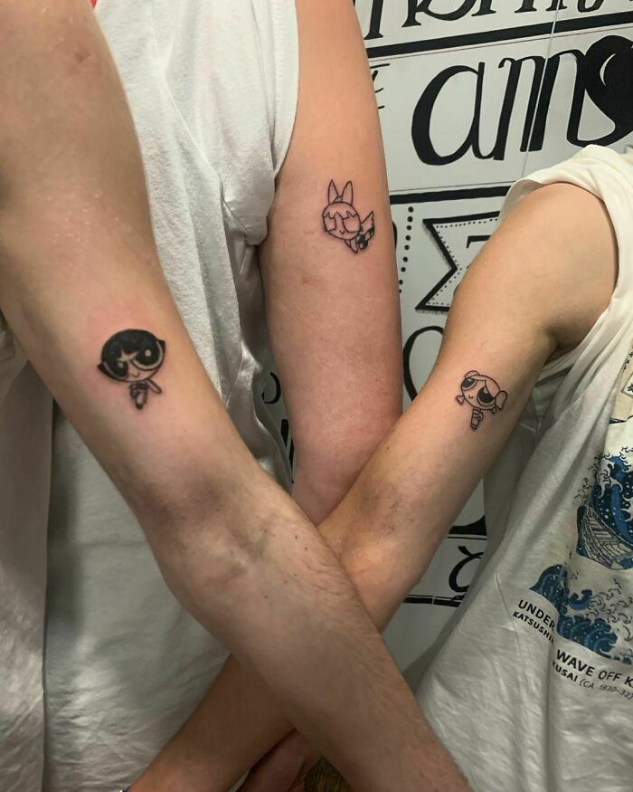 Matching best friend tattoos on arms featuring cartoon characters, symbolizing friendship.