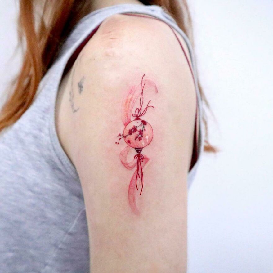 red little ball with sakura tattoo on the arm