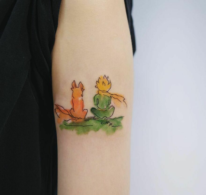 green and yellow little prince and red fox tattoo on the arm