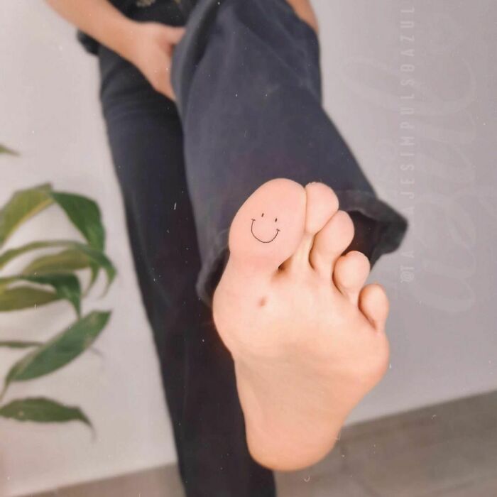 minimalistic tattoo of a smiley on toe