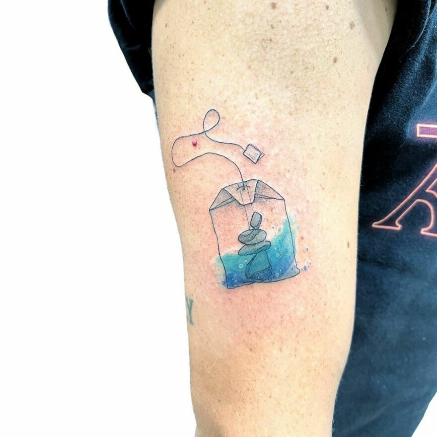 tea bag with little stones in it tattoo on the arm