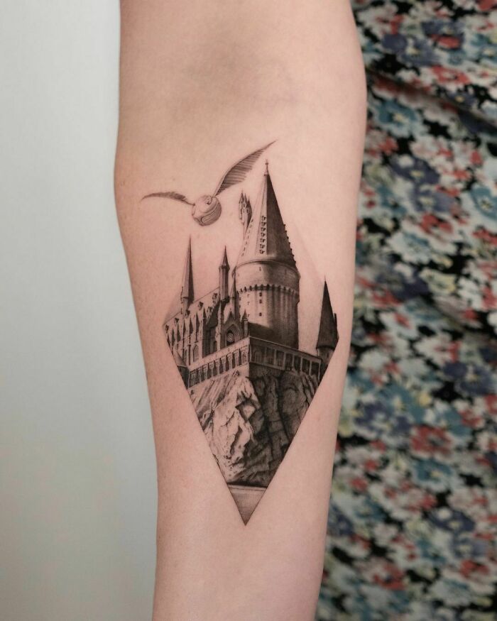 Hogwarts tattoo with flying owl on forearm, showcasing a Harry Potter design.