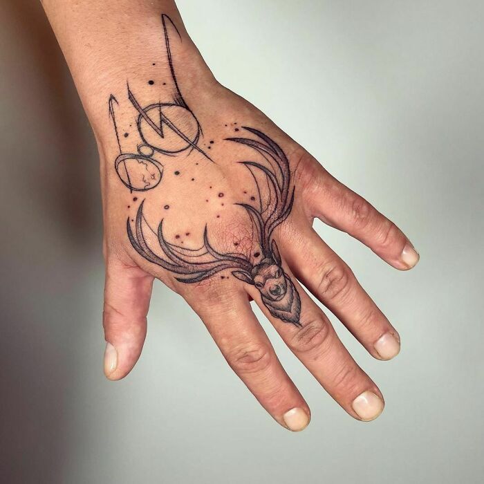 Harry Potter tattoo on a hand featuring a stag and magical symbols.