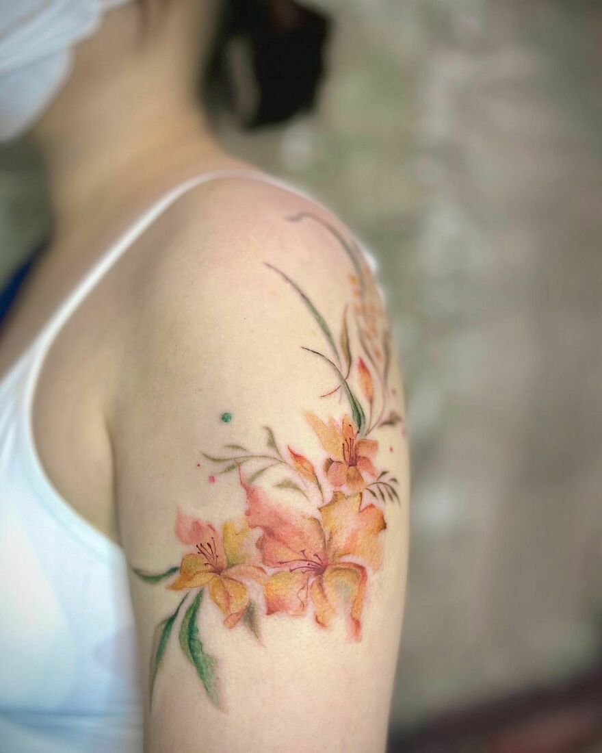 red and yellow flowers with green leaves tattoo on the arm