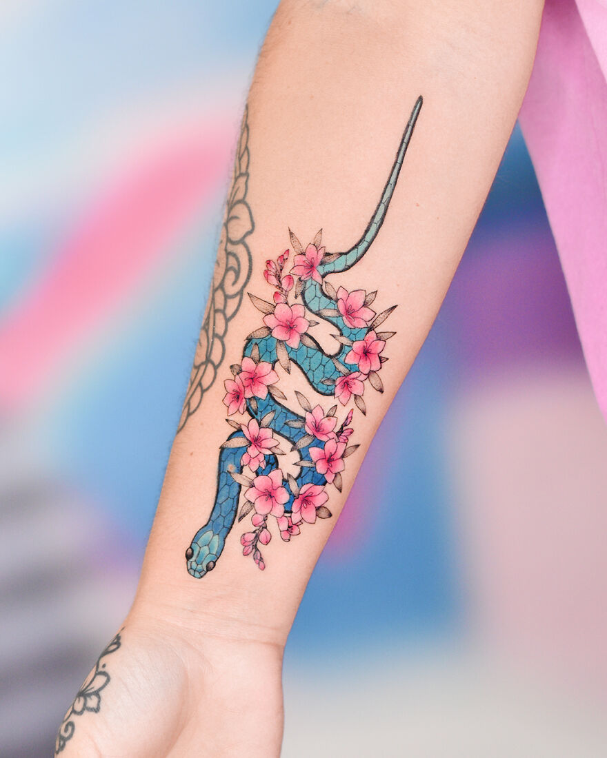 blue snake in pink flowers tattoo on the hand
